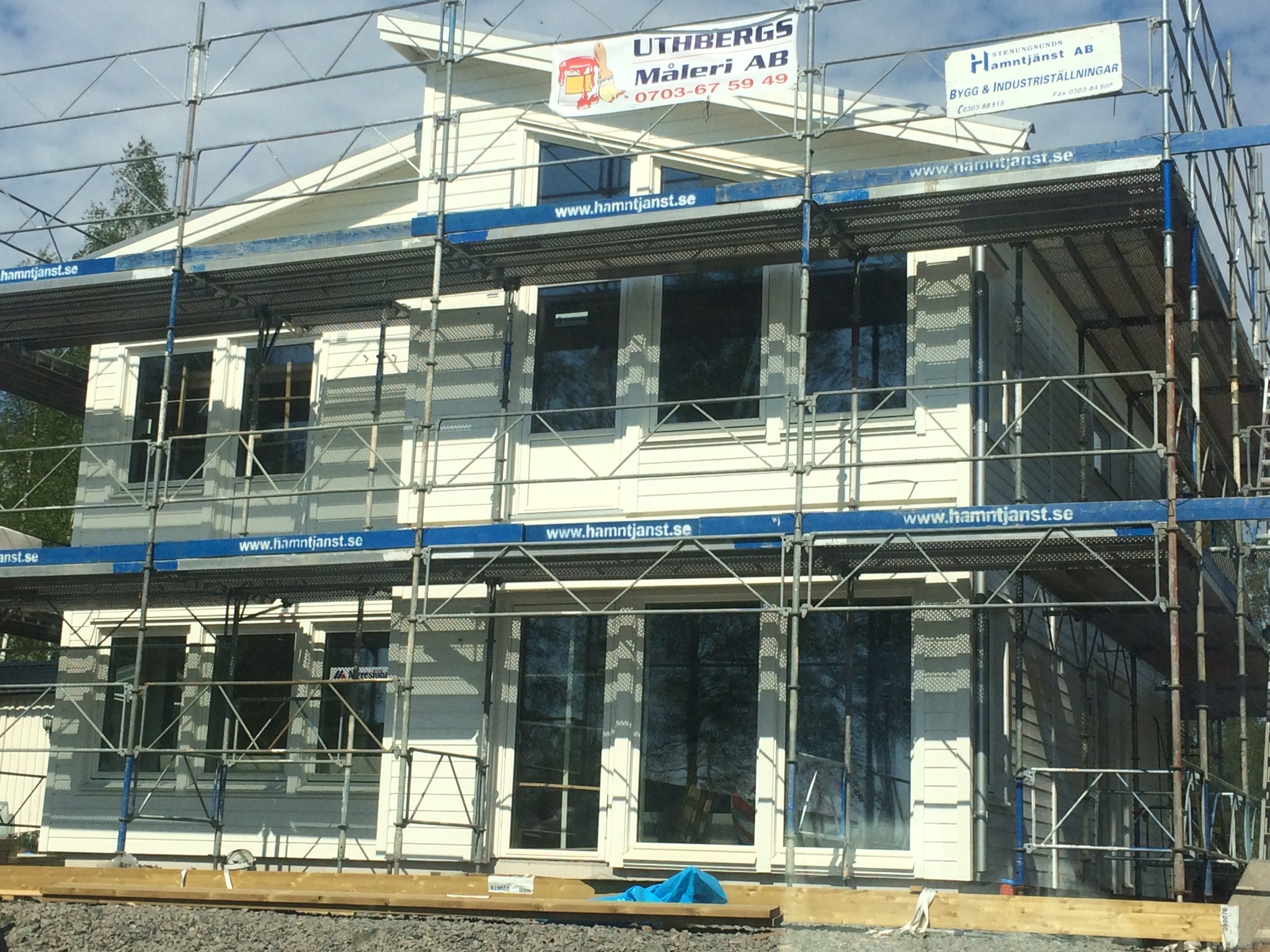 Husfasad med byggnadsställning för måleri arbete på hus, på ställningen sitter Uthbergsmåleris logotyp uppsatt